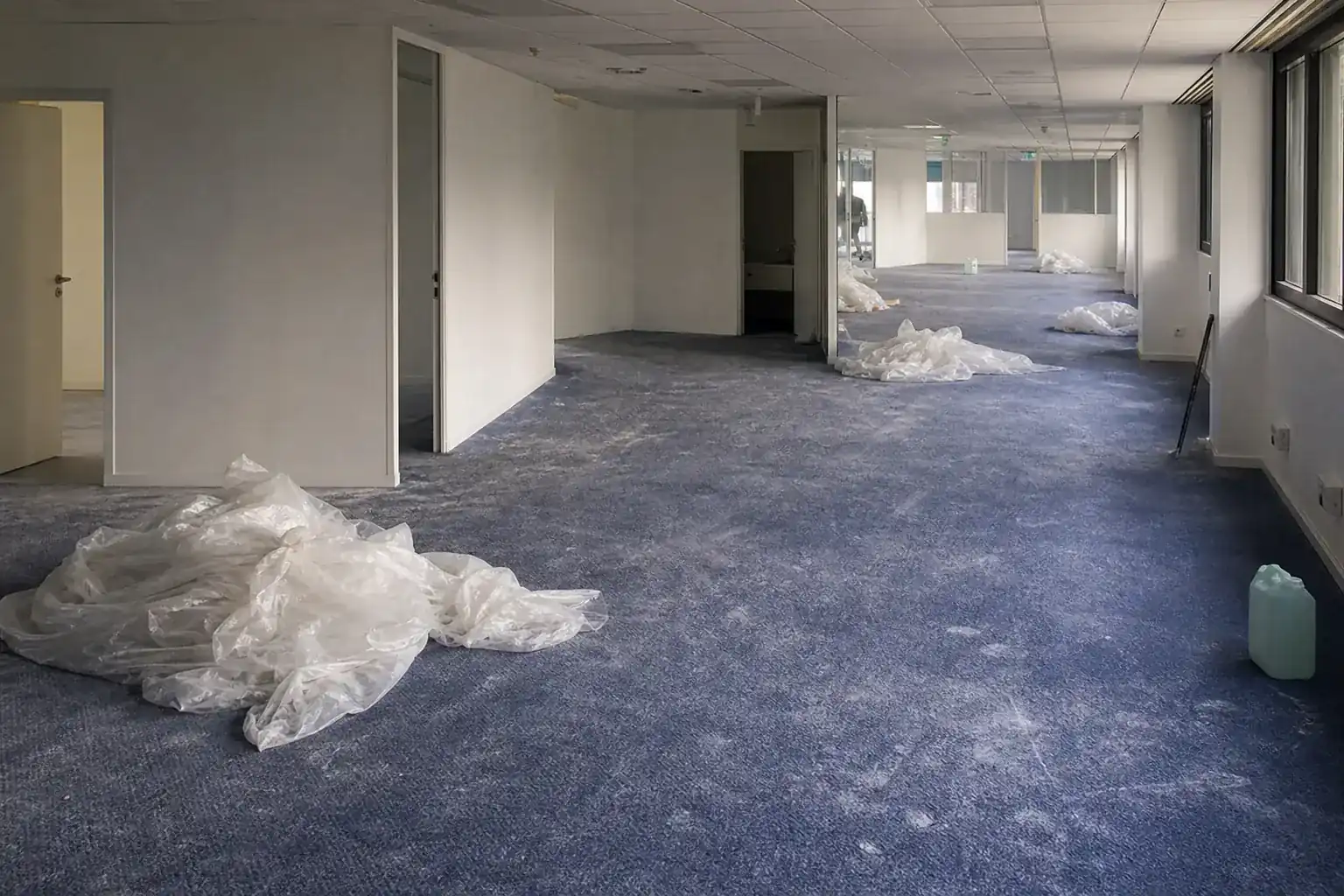 Plateau de bureaux après travaux, poussière de plâtre au sol, protections plastiques repliées